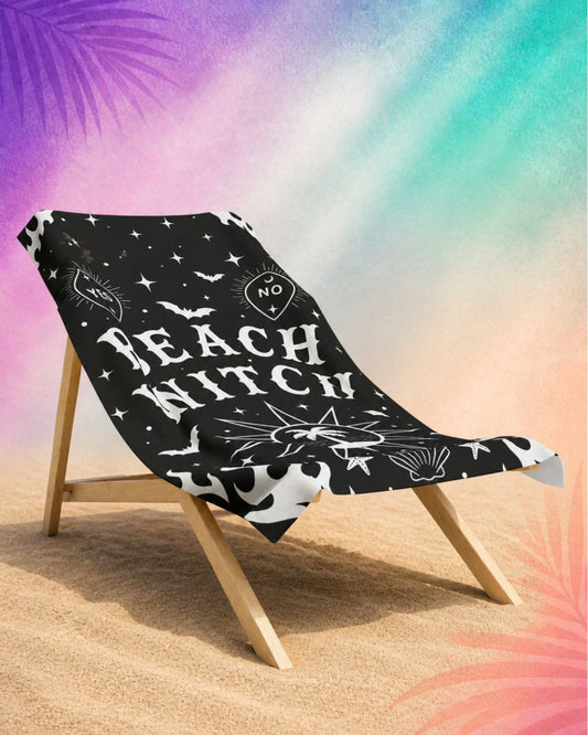 Gothic beach towel with beach witch design draped over chair, black halloween beach towel with spooky celestial elements