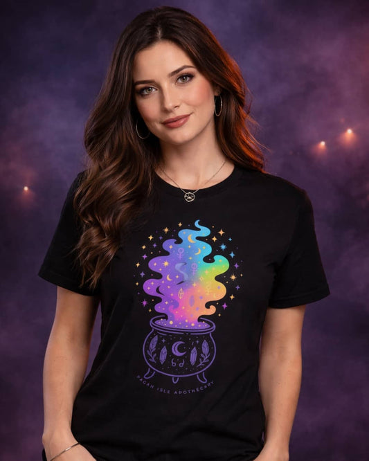 Model wearing the black Cosmic Cauldron t-shirt featuring a celestial witchy cauldron design in a dark, moody studio setting.