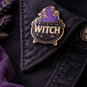 Pin with 'WITCH' text on a dark fabric background