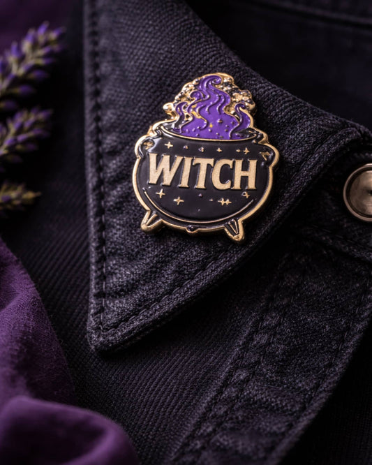 Pin with 'WITCH' text on a dark fabric background