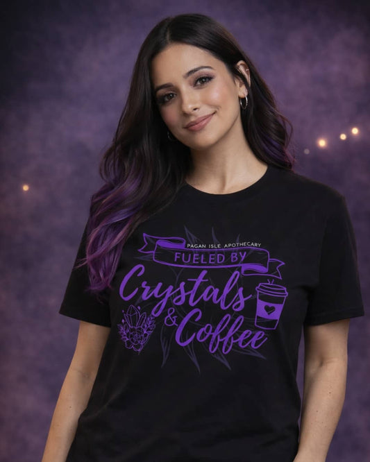 Model wearing the black Fueled by Crystals and Coffee t-shirt featuring a witchy crystal and coffee-inspired graphic in a moody studio setting.
