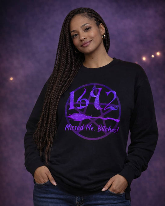 Model wearing the black Missed Me Bitches sweatshirt featuring a bold witchy statement design in a dark, moody studio setting.