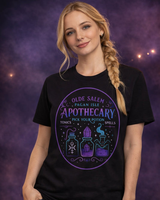 Model wearing the black Olde Salem Potion Parlor t-shirt featuring a vintage witchy apothecary-inspired design in a dark, moody studio setting.