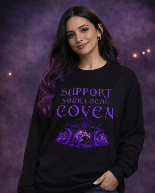 Model wearing the Support Your Local Coven sweatshirt featuring a bold witchy slogan, styled in a dark, moody studio setting.