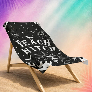 Gothic beach towel with beach witch design draped over chair, black halloween beach towel with spooky celestial elements