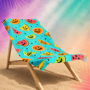 Summerween aesthetic beach towel with fruit jack o lantern design on beach chair, colorful spooky beach towel
