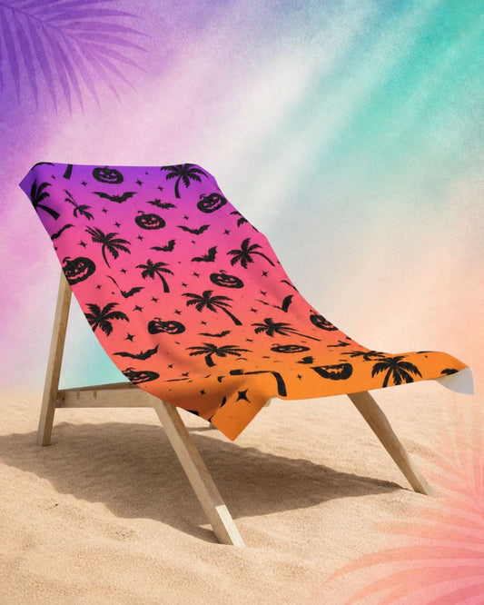 Summerween beach towel draped over beach chair with palm tree and pumpkin pattern, spooky summer beach aesthetic